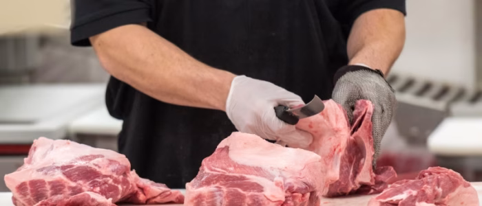 Butcher trimming meat