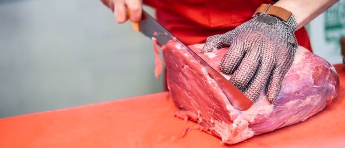 Butcher slicing meat on red board